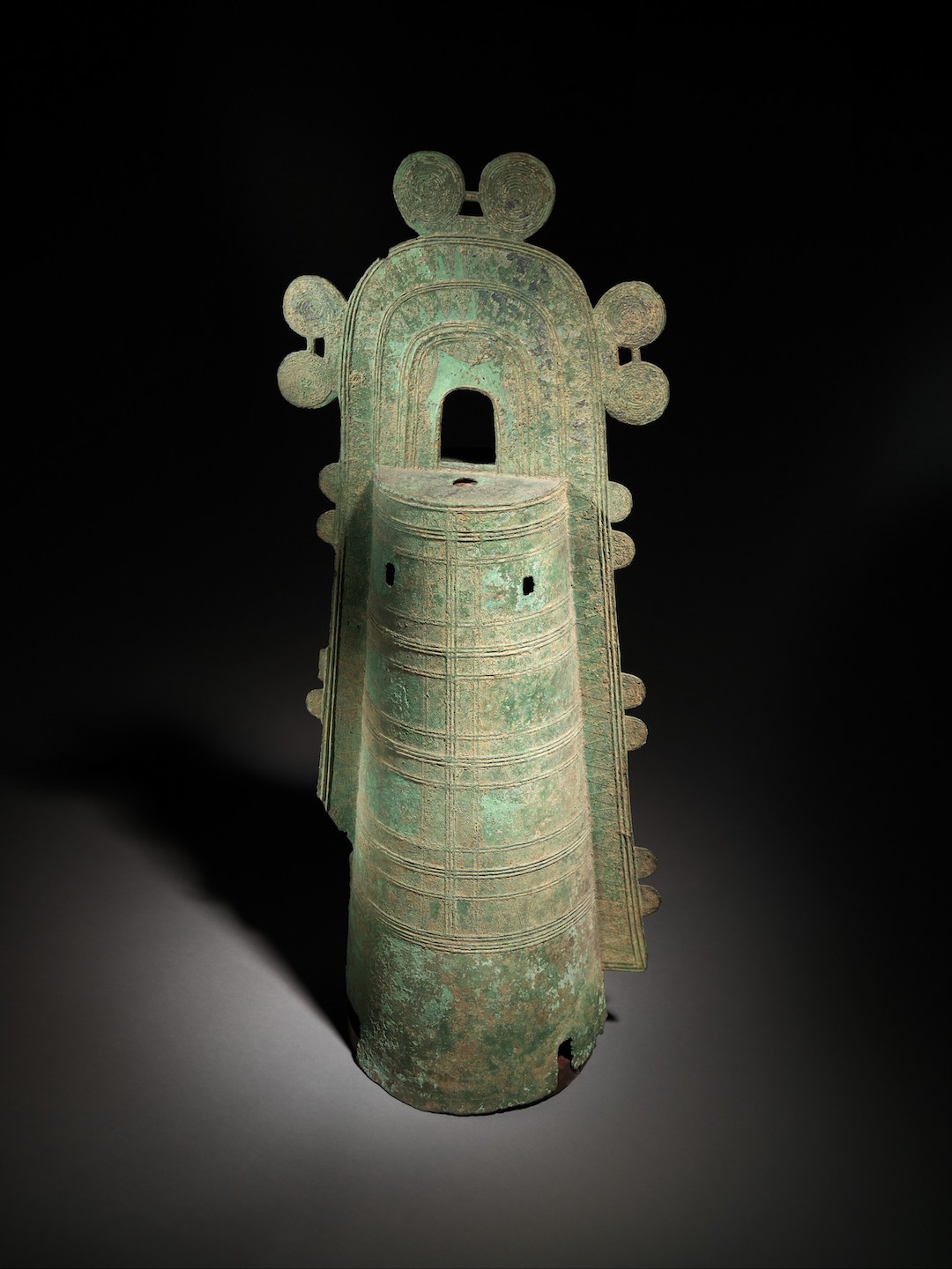 schmales, glockenförmiges Kunstwerk aus Bronze mit schnurförmigen Verzierungen im Metall