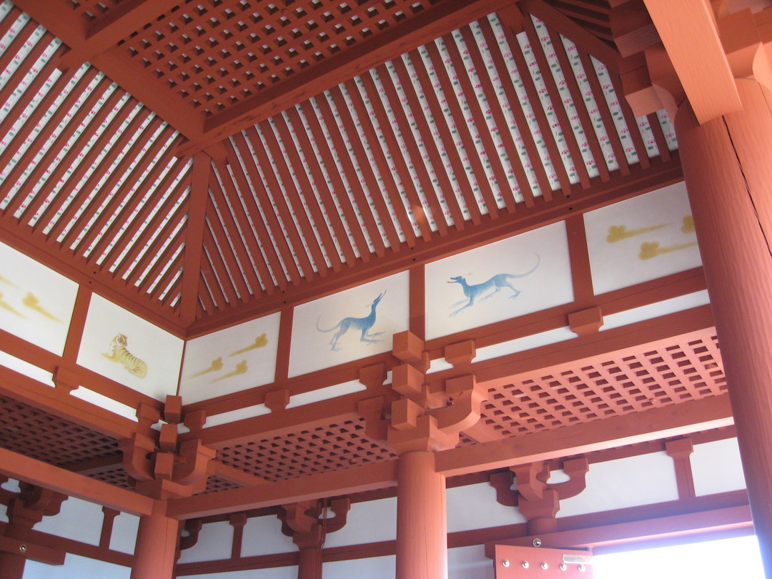 Blick zur Decke im Inneren des Palasts Daigokuden: Deckenkonstruktion von rot gestrichenen Hölzern, die fein ineinandergreifen, ohne von Nägeln zusammengehalten zu werden. Dazwischen weiße Flächen mit filigranen Malereien von Wildtieren.