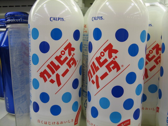 Weiße Flaschen mit blauen Punkten und roter Aufschrift: Calpis Soda.
