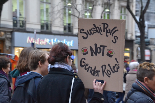Demonstrierende mit dem Plakat aus Pappkarton: „Sushi Rolls NOT Gender Roles!“